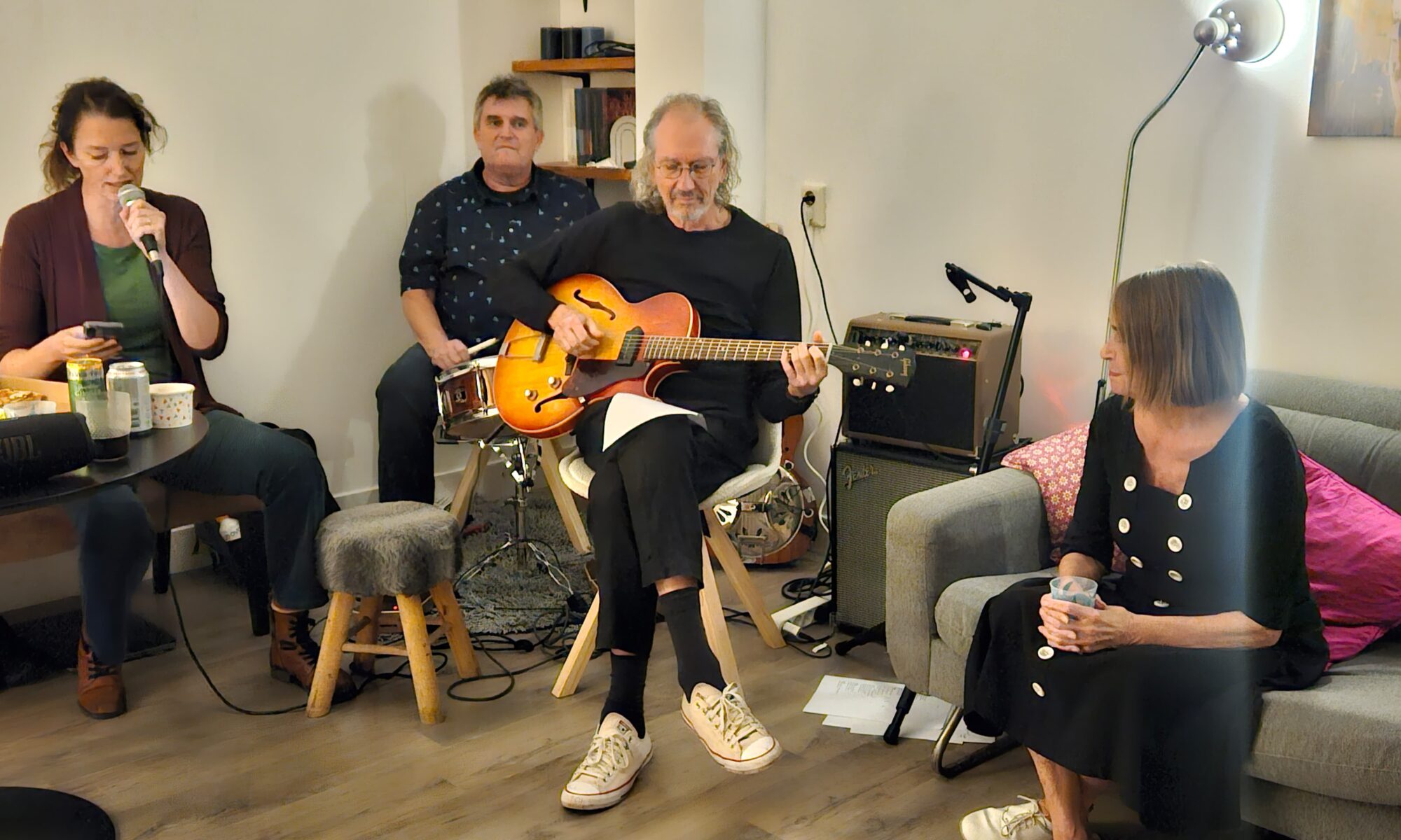 3 musicians sitting in a living room playing music
