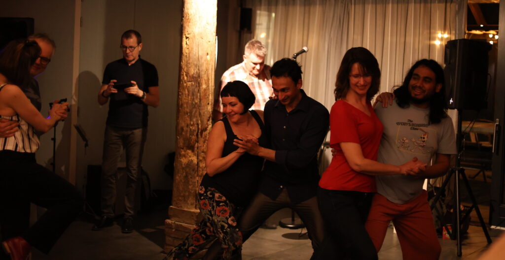 Group of people dancing a partner dance in a dark room. They are having fun.